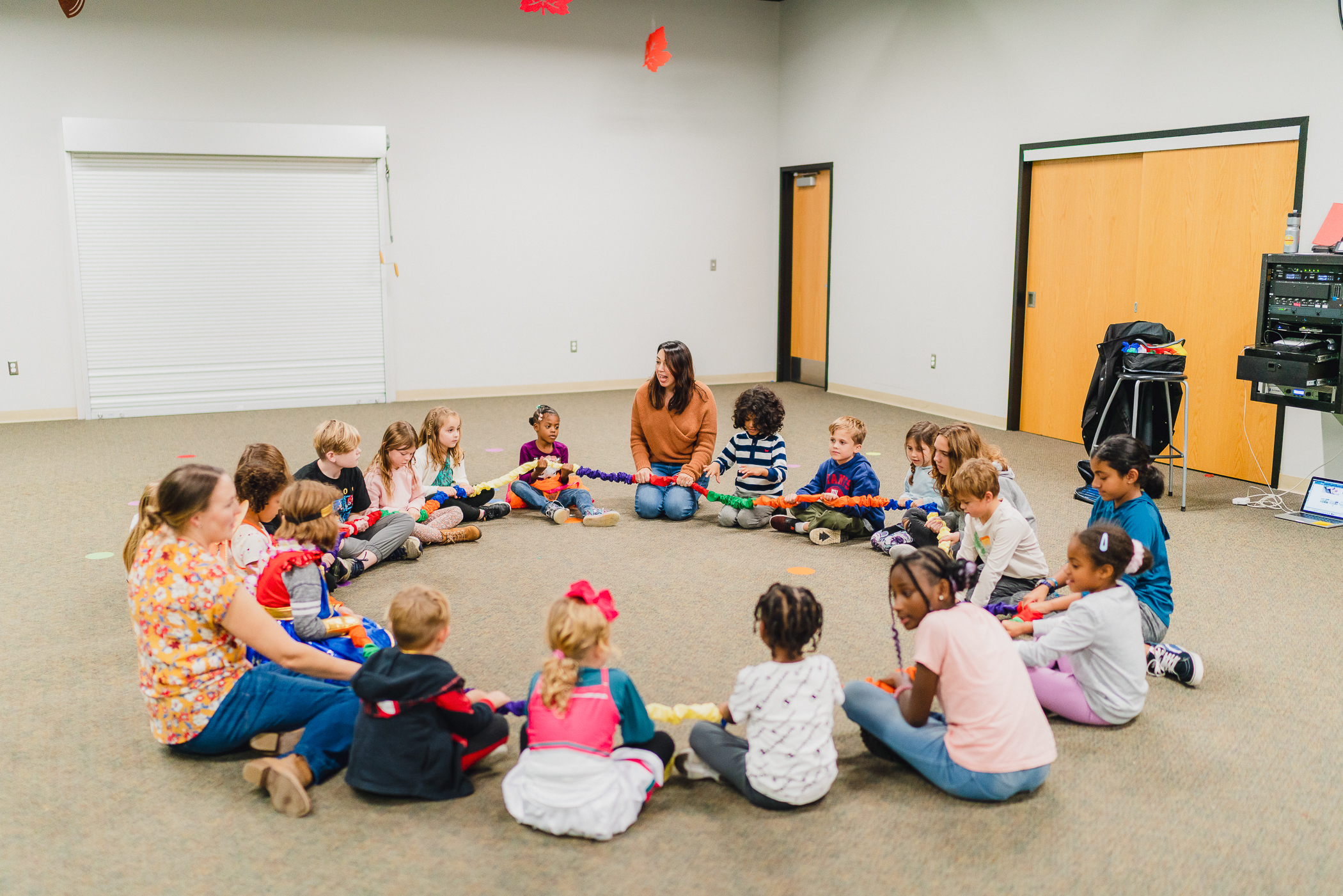 A wide view of Kazoo children and teachers gathered in a large circle for a movement game