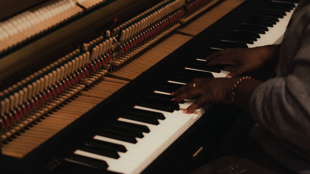 Close-up of an adult student's hands playing the upright piano during a private lesson at Kaleo